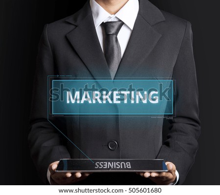 Text Marketing which arises from a hologram of a tablet held by business men with black Background.