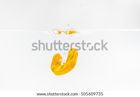 Yellow wooden alphabet U drop in the water with white background and selective focus