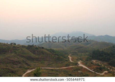 Picture of road in valley among mountains in hazy day. Mountains viewpoint are covered with smoke from forest fire.