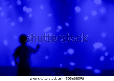 Blurry picture of silhouette children in front of blue aquarium (Jellyfish tank) - Education concept background 