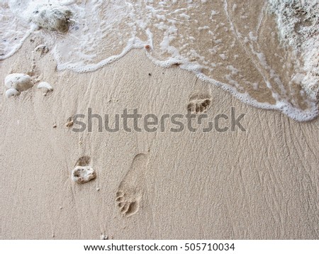 Footprints on the sand in the cave with wave washing up