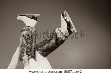 Woman legs wearing skates fur warm socks. Girl getting ready for ice skating. Winter sport activity. Studio shot b&w photo