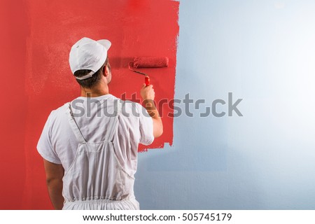 Young man painting wall with roller Royalty-Free Stock Photo #505745179