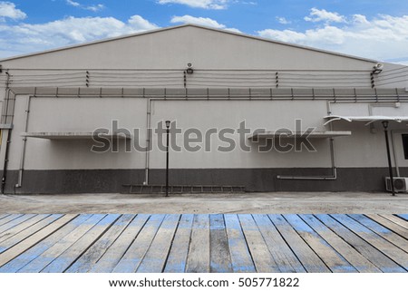 Wood floor with Modern industrial building blue sky background.