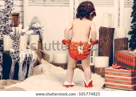 little kid standing in the Santa suit, from back, Beautiful baby celebrates Christmas, New Year's holidays, Child in a xmas costume from back, vintage photo