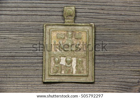 Vintage (ancient) metal (bronze, copper) orthodox icon (scapular) covered with green patina on an old wooden background. Christian ikon. Hail Mary. 