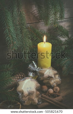 Light candle and Christmas cookies with Christmas and New Years decor and Christmas tree on dark wooden background