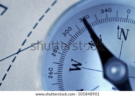 Detail of a magnetic compass on the background of the geographic map images