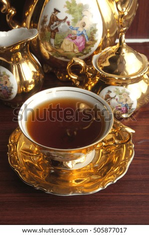 Beautiful vintage gold tea service with pictures on wood background.Isolated
