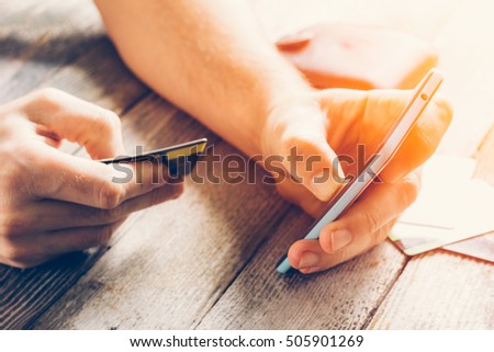 Man Hands holding credit card and using mobile phone in sunlight. Online shopping, online banking and online marketing. cyber Monday, black Friday