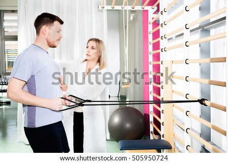 doctor physiotherapist helps a patient to restore movement and function with  gymnastics stretching  and exercises to improve performance Royalty-Free Stock Photo #505950724