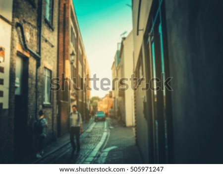 burred of a man walking along the road between old building against the light in evening time, can be used for your text or conceptual image, Vintage color