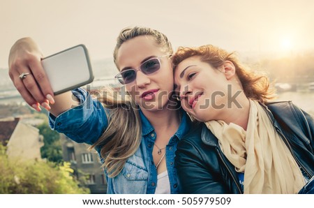 Two female friends taking a selfie with smartphone
