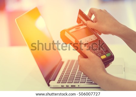 Woman hand with credit card swipe through terminal for sale in online Internet made with Vintage Tones