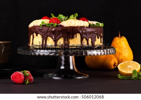 Cake with dark chocolate mousse, pear confit, fruits and berries on top as decoration. Tea party with homemade fresh cake.