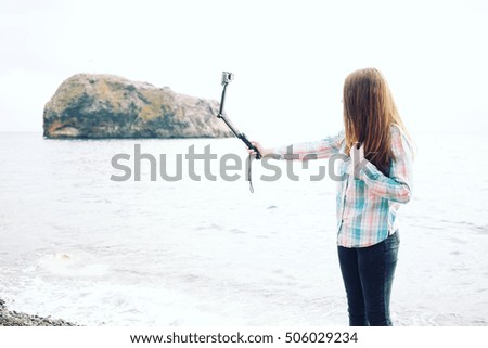 Attractive hipster girl with action camera on her hand. 