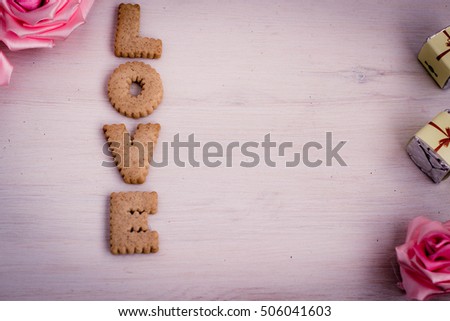 Love concept, romantic background with bisquit made letters. Cookies alphabet, wedding and date design, love message. Tender decorative roses and little gift boxes.Toned image.