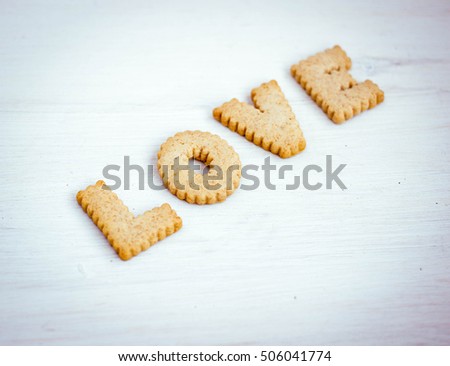 Love concept, romantic background with bisquit made letters. Cookies alphabet, wedding and date design, love message. Toned image.