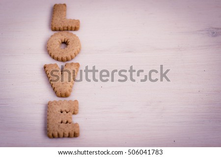 Love concept, romantic background with bisquit made letters. Cookies alphabet, wedding and date design, love message. Tender decorative roses and little gift boxes.Toned image.