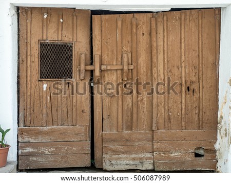 Old and abandoned wooden gate on a white wall