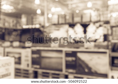 Electronic department store with bokeh blurred background. Television retail shop, TVs display on shelf at wholesale store. Defocused background of warehouse interior technology aisle. Vintage filter.