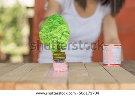 Close up paintbrush in hand and painting on the wooden table. Pink color, Brush painting wooden furniture, Woman is holding a brush and painting wood