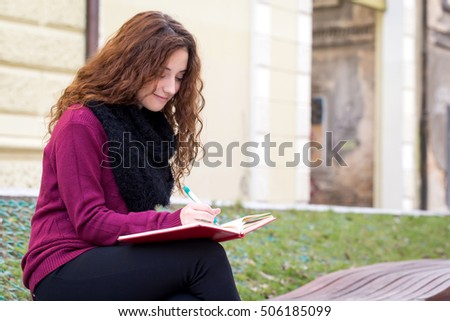 young school girl writing on an  notepad with a pen Royalty-Free Stock Photo #506185099