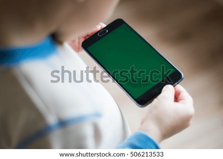 The child is holding a phone in his hand with a green screen for