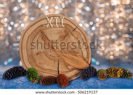 Larch saw cut in the form of dial witharrows and painted fir cones on golden bokeh background. Christmas and New Year background.