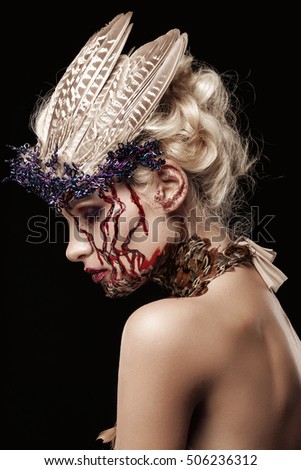Beauty photo in the studio on a black background. Beautiful girl. Close portrait. Girl with feathers on their heads. Photo Art.