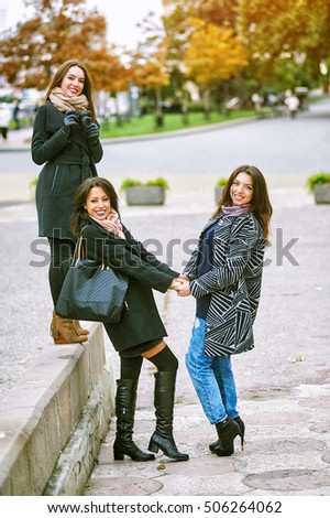 Three young attractive girls having fun taking pictures together on city walk . A way of life .