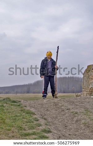 Masked man standing on a hill.