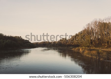 Autumn landscape with river and blue sky. Toned image.