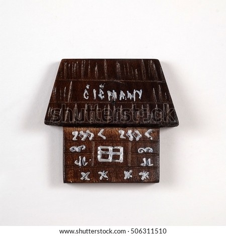 Magnetic souvenir from Slovakia with the image of a black wooden house in the village of Tchitchmany isolated on white background. The inscription on the magnet Slovak village name means "Tchitchmany"