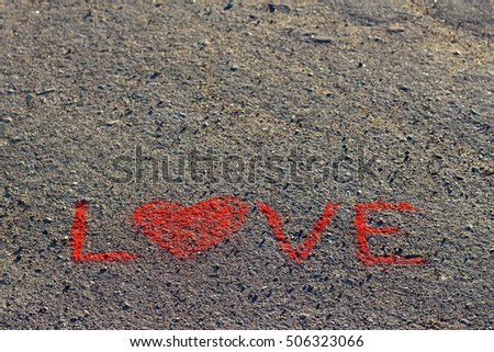 Word LOVE written on the asphalt, ground. Red color of chalk