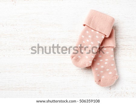 Pink baby socks on white wooden background, top view