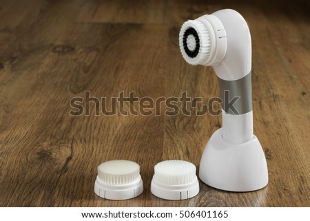 Electric brush cleanser on a wooden background.