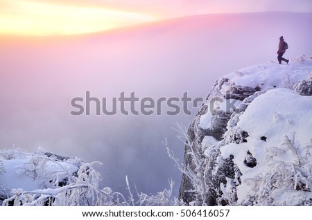 Man walking over dreamy landscape covered in snow and light of sunrise. Wallpaper for winter or christmas with space for your montage.  