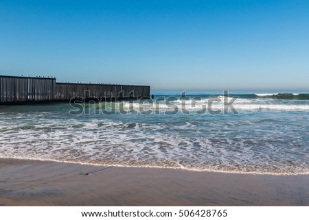Waves on beach at Border Field State Park, with the international border separating San Diego, California from Tijuana, Mexico in the background.