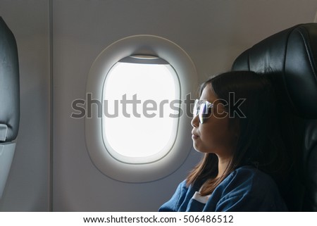 Asian girl sitting beside airplane window