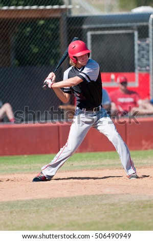 High school player swinging the bat during a game.