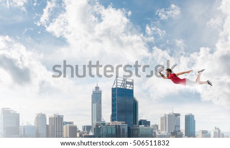 Young cheerful man flying high above city
