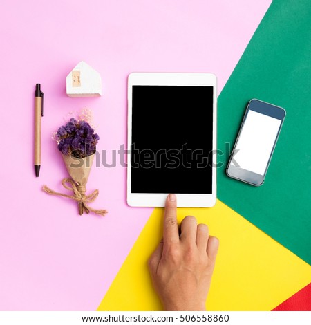 Flat lay hand using tablet and phone white screen on top view,background in pastel colors