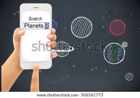 child hand with holding a smart phone and searching information of planets with homepage and blackboard with drawing planets in background
