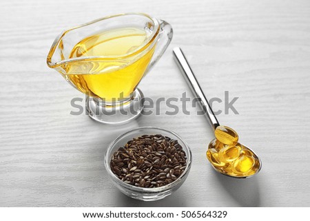 Fish oil pills in spoon and flax grain on light background