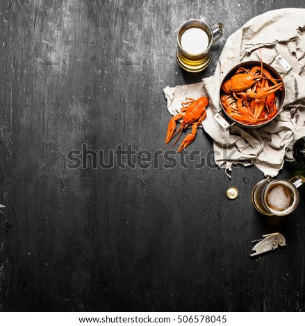Fresh boiled crawfish with beer on the old fabric. On a black chalkboard.