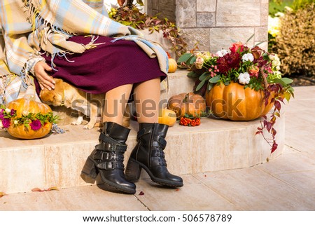 Pretty woman sitting on a porch decorated for Thanksgiving and Halloween
