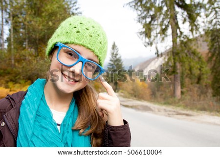 Little girl wearing glasses and hat in autumn day