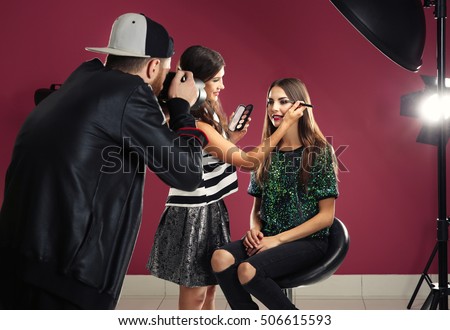 Professional makeup artist working with young beautiful woman at photo shooting
