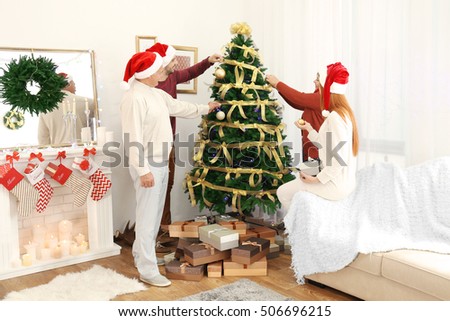 Happy family decorating Christmas tree in living room